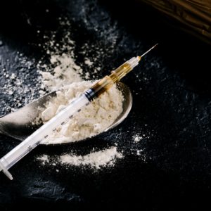 Pure Heroin in a syringe with powder displayed on a clean surface, representing substance use and addiction.