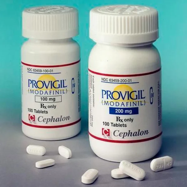 Two sealed bottles of 100mg and 200mg Modafinil (Provigil) oral tablet with a few tablets displayed on a clean surface.