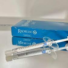 Radiesse dermal filler displayed in its original packaging alongside a syringe, showcasing its quality and authenticity for buyers and users.