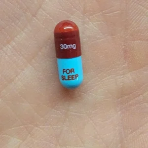 Single Restoril 30 mg capsule resting on an open palm, showcasing its size and clear labeling.