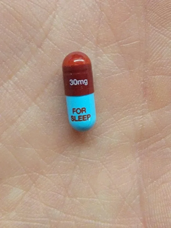 Single Restoril 30 mg capsule resting on an open palm, showcasing its size and clear labeling.