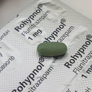 A single Rohypnol (Flunitrazepam) oral tablet displayed on a sealed card of Rohypnol packaging