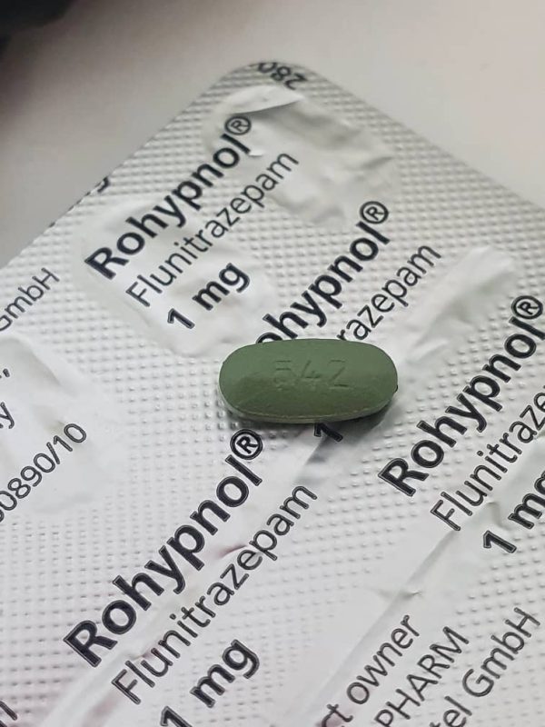 A single Rohypnol (Flunitrazepam) oral tablet displayed on a sealed card of Rohypnol packaging